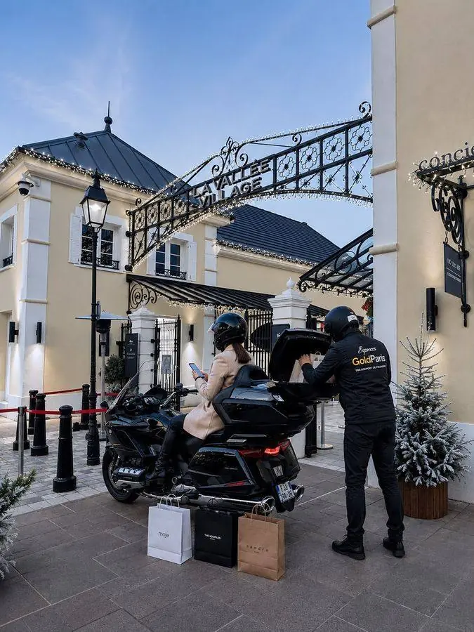 Chauffeur Express Gold Paris chargeant les achats d'une cliente à La Vallée Village